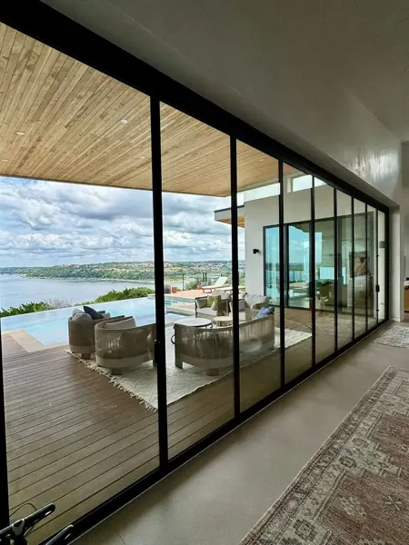 Floor-to-ceiling sliding glass wall overlooking Lake Travis and a pool